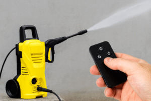 Lavadora de alta pressão amarela sendo acionada à distância por um controle remoto preto.